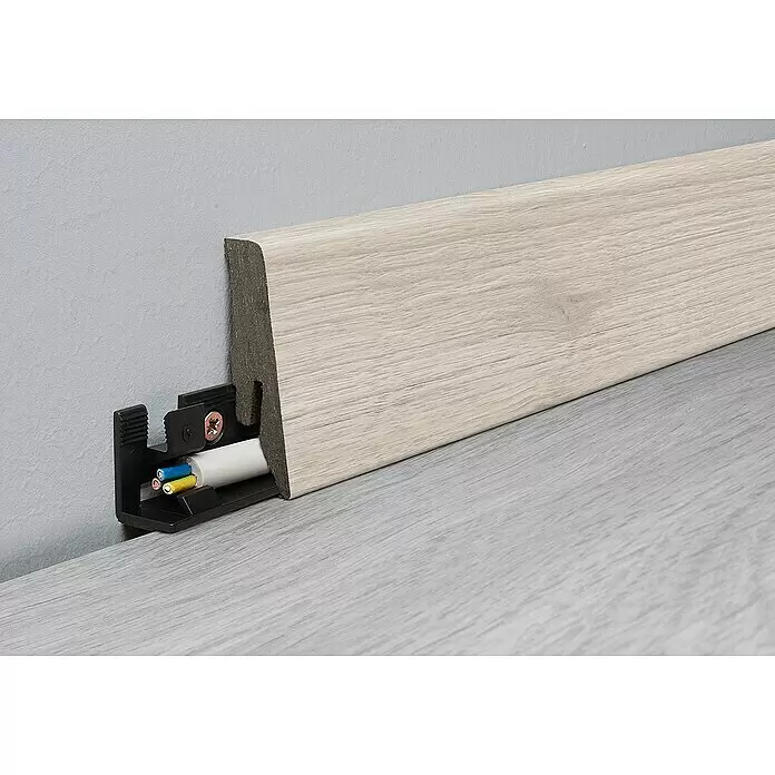 LOGOCLIC Sockelleiste Element Flex Eiche Callida - 260 cm x 18 mm x 58 mm, MDF/HDF - Helle, holzgemaserte Fußleiste mit integriertem Kabelkanal, der blaue, gelbe und grüne Kabel enthält. An einer Wand über einem hellgrauen Boden montiert.