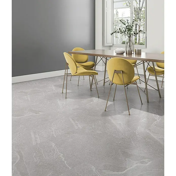 Pavimento porcelánico Aura - 60,5 x 60,5 cm, Light, Mate - Comedor luminoso con mesa y sillas amarillas sobre un suelo gris con efecto mármol, complementado con decoración de ventana y color de pared.