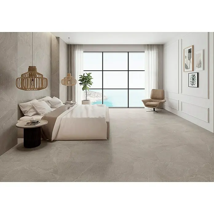 Pavimento porcelánico Aura - 60,5 x 60,5 cm, Earth, Mate - Un dormitorio luminoso con una gran ventana con vistas al mar y baldosas de color gris claro que añaden un toque elegante a la habitación.