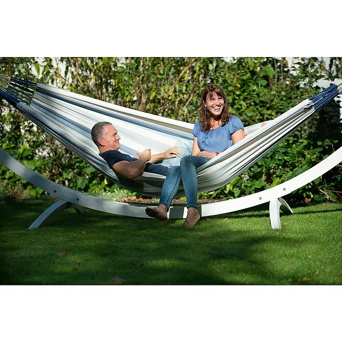 La Siesta Hängematte Brisa Kingsize - L x B: 400 x 180 cm, Sea Salt - Entspanntes Paar genießt die Sonne in einer stilvollen Streifen-Hängematte mit weißem Gestell auf einer grünen Wiese.