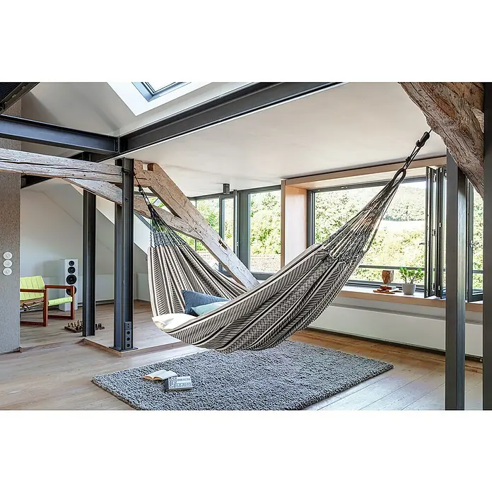 La Siesta Doppelhängematte Flora - L x B: 400 x 180 cm, Zebra, Ausführungseigenschaft: Kingsize - Innenaufnahme eines Zimmers mit einer stilvollen, gestreiften Hängematte, die zum Entspannen einlädt. Die Hängematte hängt zwischen Holzbalken und Stahlträgern.