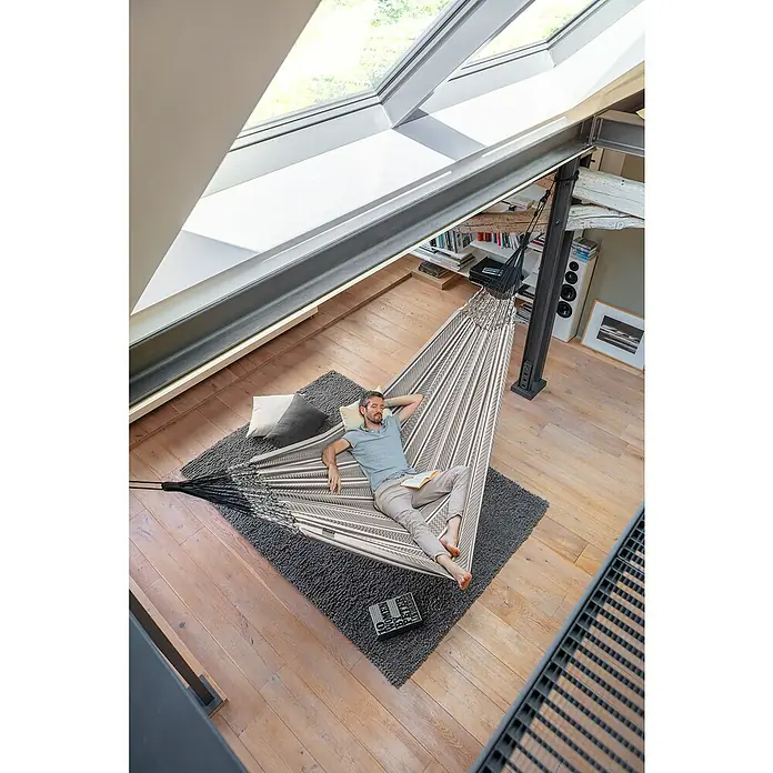 La Siesta Doppelhängematte Flora - L x B: 400 x 180 cm, Zebra, Ausführungseigenschaft: Kingsize - Ein Mann entspannt in einer gestreiften Hängematte auf einem weichen Teppich in einem hellen Raum. Die Hängematte bietet Komfort und Stil.