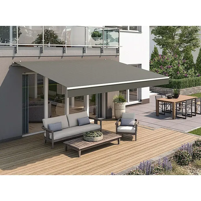 Solid Elements Gelenkarmmarkise 320925Dunkelgrau strukturiert, Breite: 3 m, Ausfall: 2,5 m - Terrasse mit einer grauen Gelenkarmmarkise, die Schatten spendet und einladenden Sitzbereich mit Couch, Sessel und Tisch bietet.