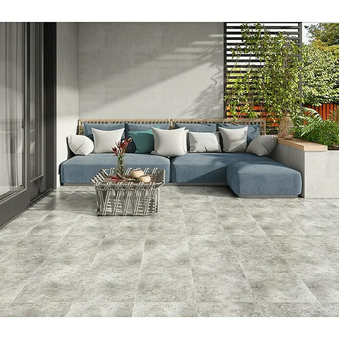 Halcón Pavimento porcelánico Medellín - 33,3 x 33,3 cm, Gris, Mate - Acogedor patio con un moderno sofá lounge, una elegante mesa de centro y un piso de baldosas grises que crea un ambiente relajante.