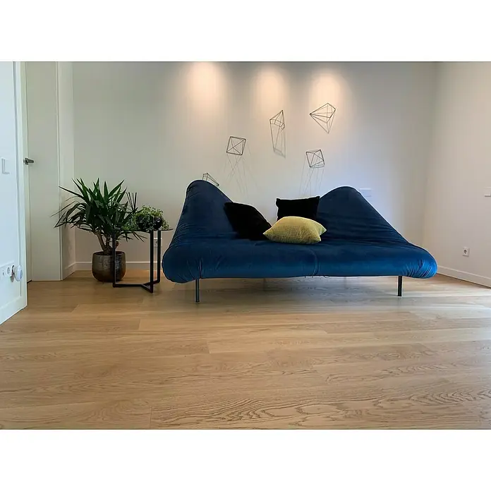 Parkett Eiche Mosel - 1.700 x 190 x 15 mm, Landhausdiele - Wohnzimmeransicht mit einem blauen Sofa, das mit schwarzen und gelben Kissen verziert ist, und einer Pflanze auf einem Beistelltisch.