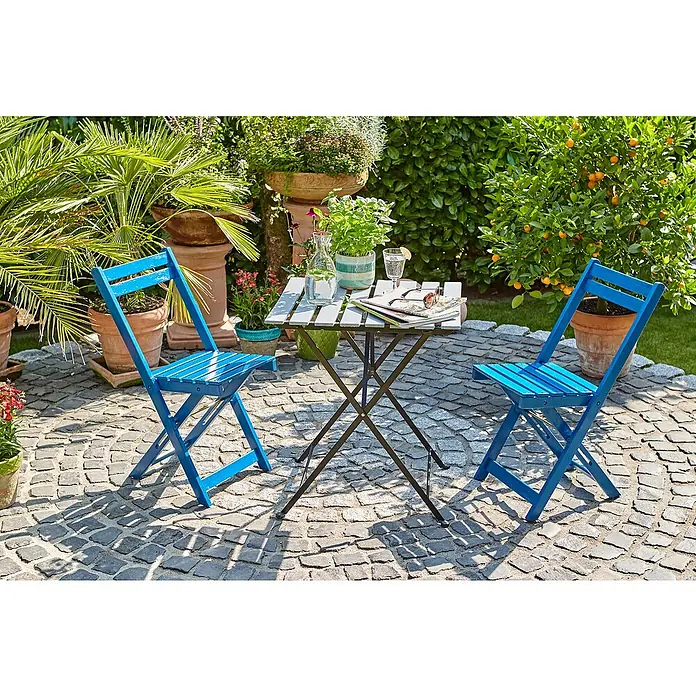 swingcolor Buntlack Kunstharz für AußenSilbergrau, Seidenmatt, 750 ml, Lösemittelbasiert - Einladende Gartenszene mit blauem Tisch und Stühlen auf Pflastersteinen, umgeben von üppigem Grün und Pflanzen in Tontöpfen, perfekt für entspannte Stunden.