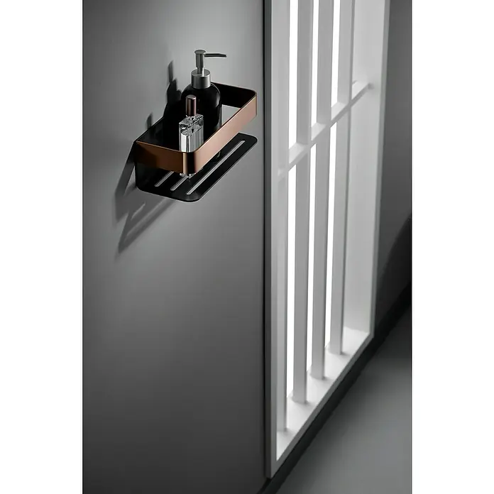 Imex Cesta de baño Mayura - 11 x 25,6 x 8 cm, Acero inoxidable, Negro/Oro rosa - Elegante estante de baño con champú y perfume. El estante está hecho de metal negro con detalles de cobre y cuelga de una pared gris.
