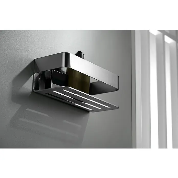 Imex Cesta de baño Mayura - 11 x 25,6 x 8 cm, Acero inoxidable, Níquel - Primer plano de un estante de ducha plateado brillante con un diseño de listones, montado en una pared gris, que presenta una botella oscura en su interior.