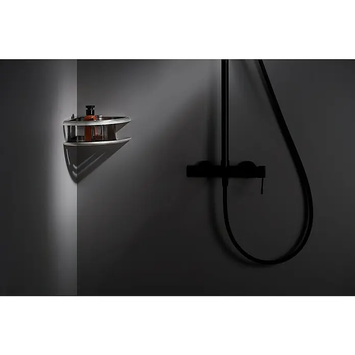 Imex Cesta de baño angular Dhanu - 20 x 20 x 9 cm, Acero inoxidable, Níquel - Elegante estante de esquina con frascos de champú y un accesorio de ducha negro contra una pared oscura del baño.