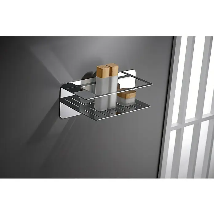 Imex Cesta de baño Bethari - 12,7 x 36 x 13,5 cm, Acero inoxidable, Cromo - Imagen de una estantería de ducha cromada de dos niveles con productos de higiene, fijada en una pared gris en el baño.