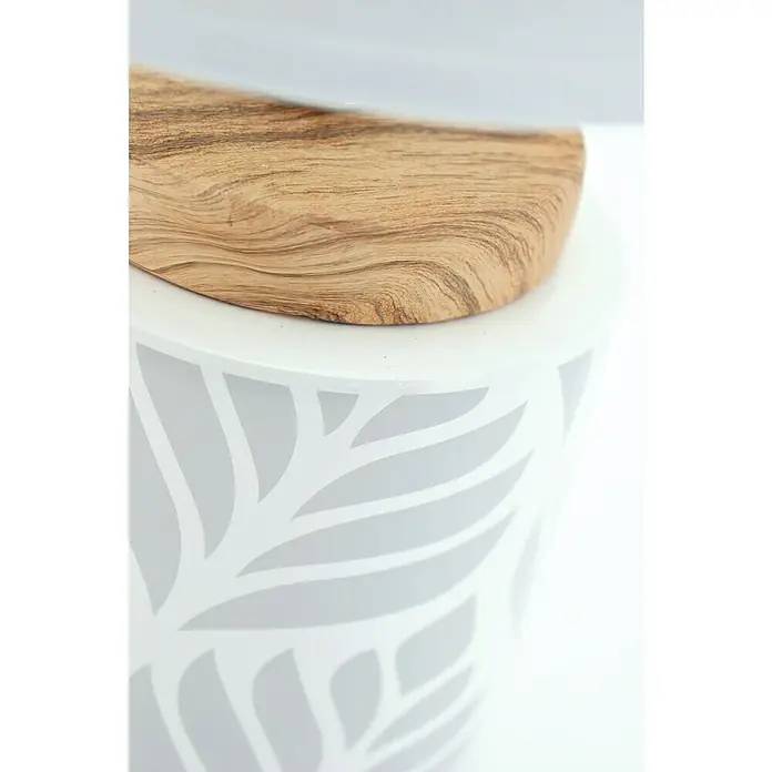 Idp Lampshades Lámpara de sobremesa Vadim - 40 W, L x An x Al: 14 x 14 x 30 cm, Blanco, E14 - Primer plano de una mesa auxiliar blanca con un patrón de hojas, coronada con una pieza de madera, que combina estéticas naturales y modernas.