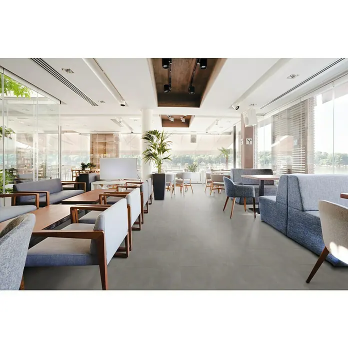 Allure Suelo vinílico SPC Concrete Pewter - 914 x 457 x 6,5 mm, Gris - Interior de un restaurante moderno y luminoso con cómodos asientos y grandes ventanales que dejan entrar mucha luz natural.