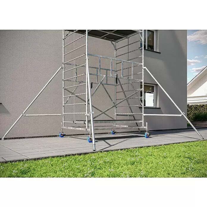 Krause ProTec XXL Rollgerüst Breitaufbau - Arbeitshöhe: 11,3 m, Belastbarkeit Plattform: 480 kg - Silberfarbenes, fahrbares Aluminiumgerüst mit blauen Rädern und dunklen Plattformen, neben einer Hauswand für Bauarbeiten aufgestellt.