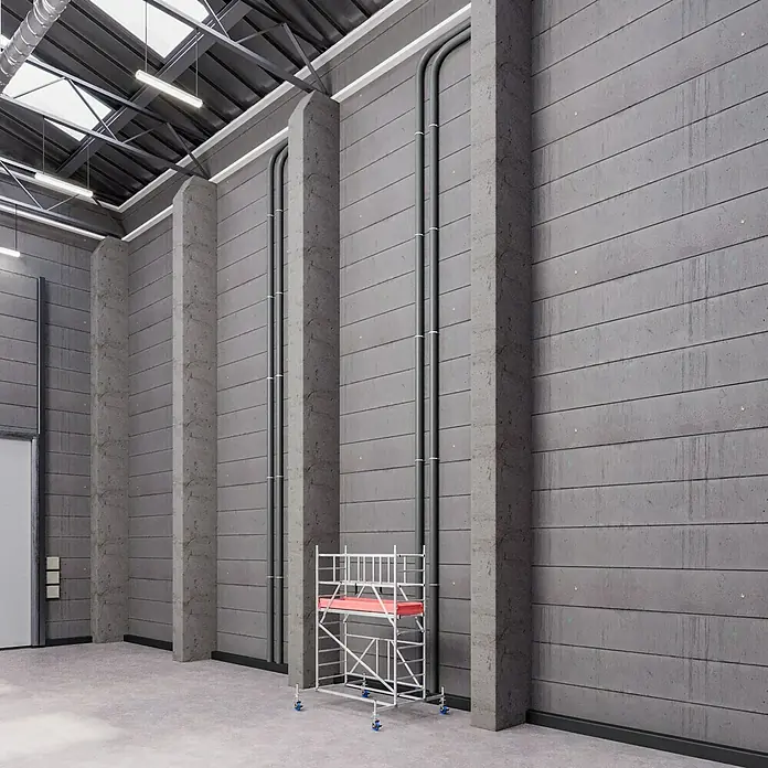 Krause ProTec XS Klappgerüst - Arbeitshöhe: 3,8 m, Belastbarkeit Plattform: 240 kg - Ein Gerüst mit roten Akzenten steht in einem Raum mit Betonwänden und Rohrleitungen. Ideal für Bau- oder Renovierungsprojekte.