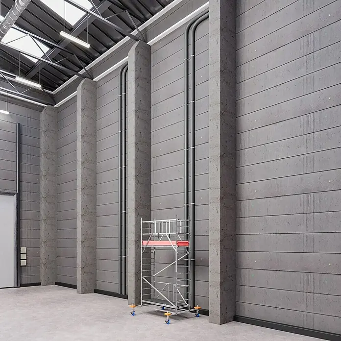 Krause ProTec XS Klappgerüst - Arbeitshöhe: 4,8 m, Belastbarkeit Plattform: 240 kg - Das Bild zeigt ein industrielles Gerüst vor einer Betonwand in einer Lagerhalle. Das Gerüst hat eine rote Plattform und blaue Rollen.