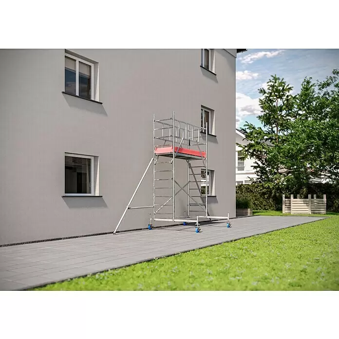 Krause ProTec Rollgerüst - Arbeitshöhe: 4,3 m, Belastbarkeit Plattform: 240 kg - Silbernes Rollgerüst mit roter Plattform, neben einem Gebäude für Arbeiten in der Höhe platziert.