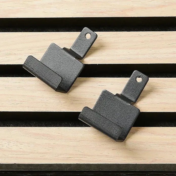 Millex Paneelkrallen Horizontal & Vertikal - L x B x H: 2,2 x 3 x 4,7 cm, Passend für: Akustikpaneele, Montageart: Einhängen - Nahaufnahme von zwei schwarzen Haken zur Befestigung an Holzlatten, ideal für Wandpaneele oder DIY-Projekte.