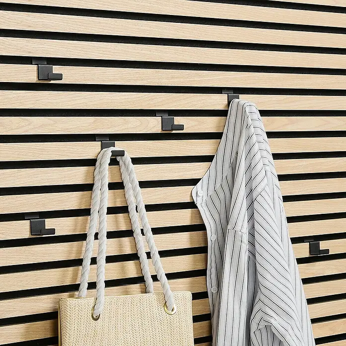 Millex Wandhaken Horizontal - L x B x H: 2,2 x 3 x 4,7 cm, Passend für: Akustikpaneele, Montageart: Einhängen - Wandpaneel mit schwarzen Haken. An den Haken hängen eine Handtasche und ein Hemd mit Streifen.