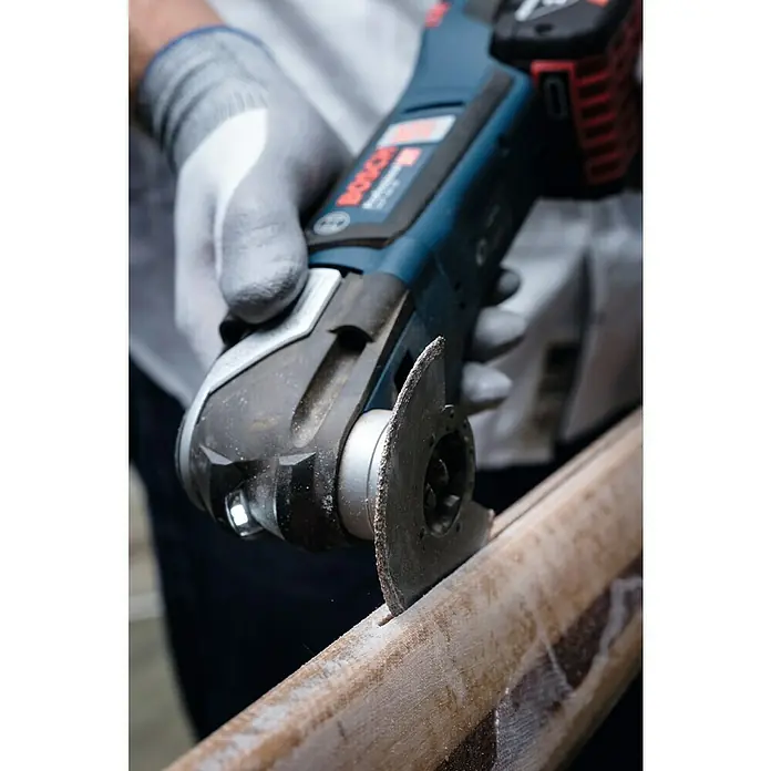 Bosch Professional Akku-Multifunktionswerkzeug GOP 12V-28 - 12 V, Ohne Akku, Mit L-Boxx - Nahaufnahme eines Bosch Multifunktionswerkzeugs beim Schneiden eines Holzstücks, bedient von einer Person mit Handschuhen.