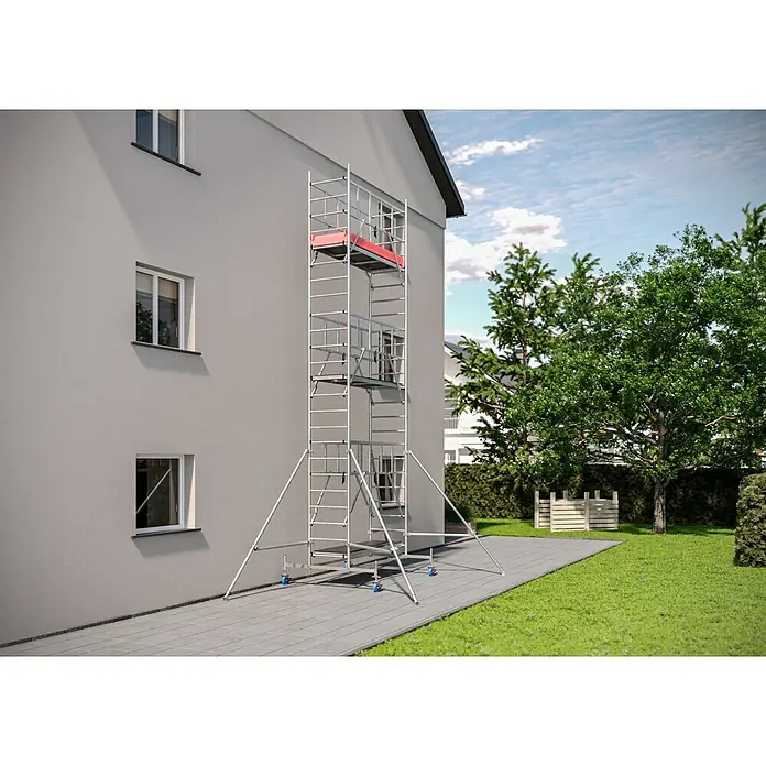 Krause ProTec Rollgerüst - Arbeitshöhe: 7,3 m, Belastbarkeit Plattform: 240 kg - Ein hohes Gerüst aus Metall steht vor einem grauen Gebäude, umgeben von Grün.