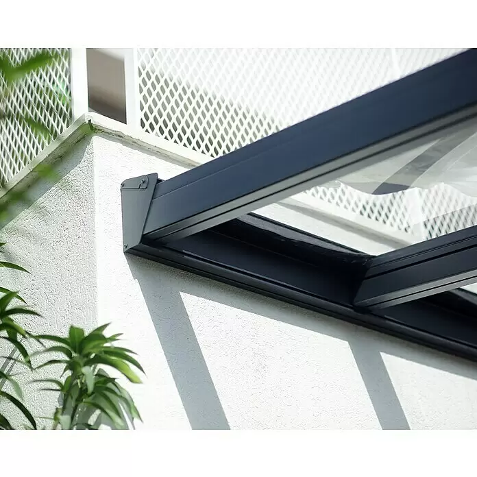 Palram – Canopia Terrassenüberdachung Stockholm - B x T: 660 x 340 cm, Anthrazitgrau, Polycarbonat - Anthrazitfarbenes Metall- und Glasvordach, an einer weißen strukturierten Wand montiert.