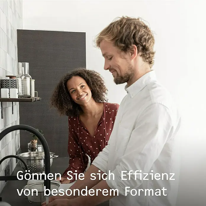 Stiebel Eltron Durchlauferhitzer DCE 11/13 - 13,5 kW, Elektronisch, Geschlossen - Ein Paar in der Küche. Die Frau lächelt, während der Mann spült. Sie genießen die Effizienz des besonderen Formats.