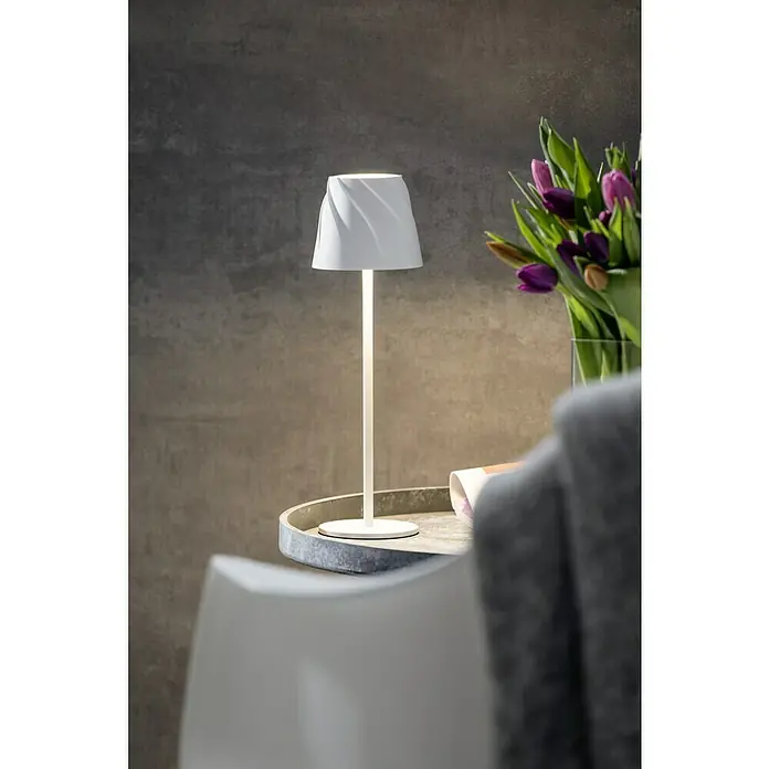 Starlux Akku-Tischleuchte Loreo - 4 W, L x B x H: 11 x 11 x 36 cm, Weiß, Warmweiß - Elegante weiße Lampe auf einem Tisch, neben einem Blumenstrauß. Die Lampe besticht durch ihr spiralförmiges Design und warmes Licht.