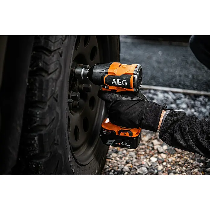 AEG Pro 18V Llave de impacto de batería BSS18MTF12BL-0 - 18 V, Sin batería, 785 Nm - Primer plano de una llave de impacto AEG que se utiliza en una rueda de coche oscura con tuercas.