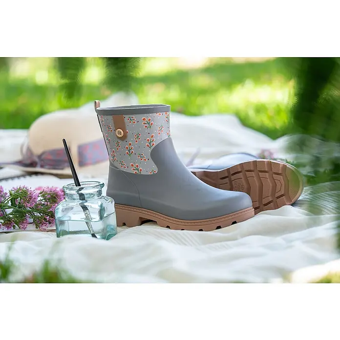 Black Fox Gummistiefel Bella - Schuhgröße: 41, Grau - Graue Gummistiefel mit Blumenmuster und brauner Sohle auf einer weißen Decke im Grünen.