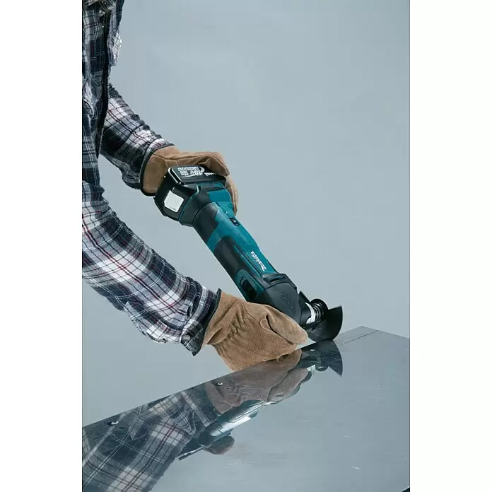 Makita LXT 18V Akku-Rotationswerkzeug DTM51Z - 18 V, Li-Ionen, Ohne Akku - Akku-Winkelschleifer von Makita, türkis-schwarz, von behandschuhten Händen beim Schleifen von Metall gehalten.