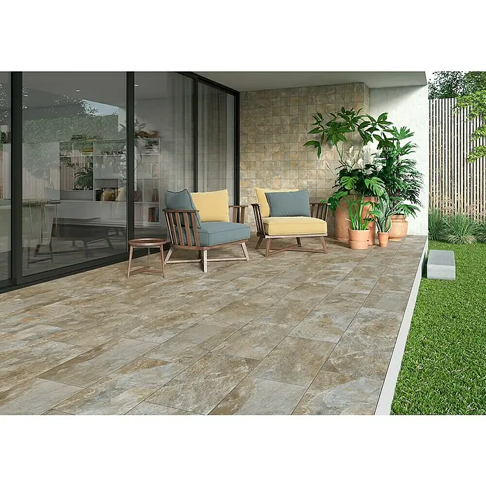 Decocer by Cinca Feinsteinzeugfliese Splash Grege - 30 x 60 cm, Braun, Matt - Einladende Terrasse mit Outdoor-Fliesen in Natursteinoptik, bequemen Sesseln und üppigen Pflanzen für eine entspannte Atmosphäre im Freien.