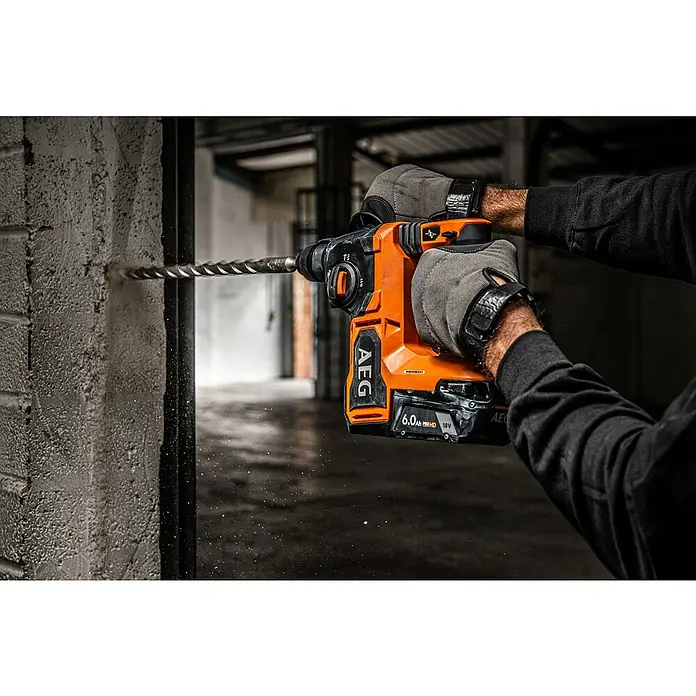 AEG Pro 18V Akku-Kombihammer BBH18BL2-0 - 18 V, Ohne Akku, 2,5 J - Ein AEG Akku-Bohrhammer im Einsatz, der kraftvoll in eine Betonwand bohrt. Der Bohrhammer ist orange und schwarz, ausgestattet mit einem 18V Akku.