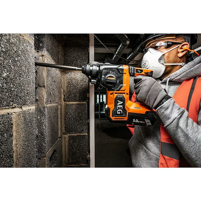 AEG Pro 18V Akku-Kombihammer BBH18BL2-018 V, Ohne Akku, 2,5 J - AEG Akku-Bohrhammer im Einsatz. Der Bohrhammer ist orange und schwarz mit einem 5.0Ah Akku und bohrt in eine Betonwand.