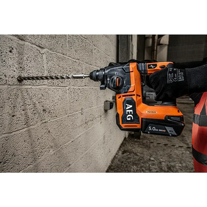 AEG Pro 18V Akku-Kombihammer BBH18BL2-018 V, Ohne Akku, 2,5 J - Nahaufnahme eines AEG-Bohrhammers beim Bohren in eine Wand, mit Akku und Bohrer im Fokus.