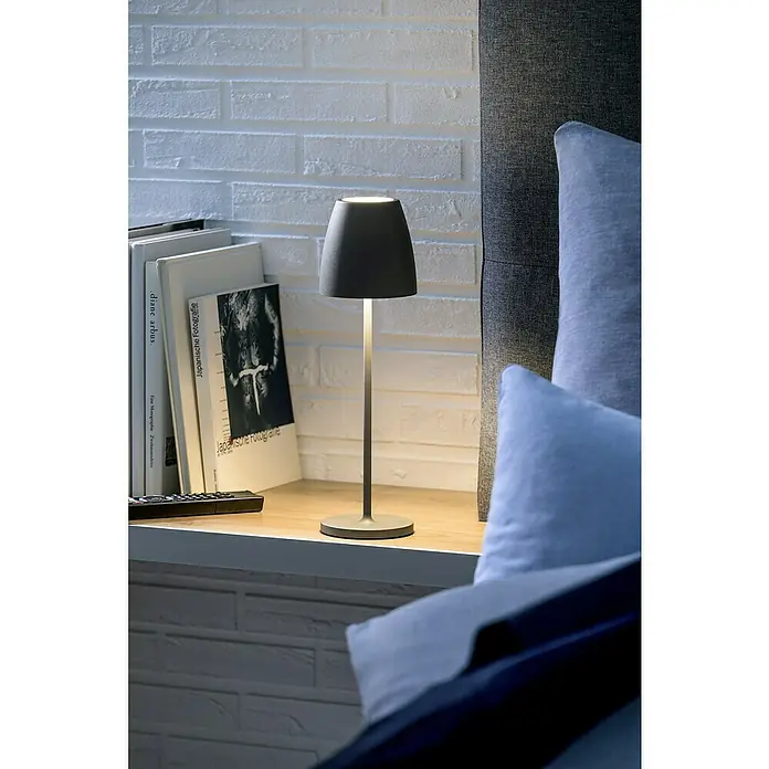 Lavida Akku-Tischleuchte Silea - 3,3 W, Anthrazit, Lichtfarbe: RGBW - Nahaufnahme einer grauen Nachttischlampe neben Büchern auf einem Nachttisch.