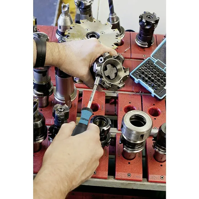 Hazet Bithalter 810SPC-6.3 - Länge: 210 mm, Magnetisch - Nahaufnahme von einer Person, die mit einem HAZET Schraubendreher an einem Werkzeughalter arbeitet, umgeben von anderem Werkzeug.