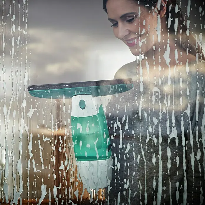 Leifheit Akku-Fenstersauger Dry & Clean - 1 Akku, Behältervolumen: 0,1 l - Eine Frau benutzt einen Fensterreiniger, um ein Fenster zu putzen. Der innovative Fensterreiniger sorgt für streifenfreie Sauberkeit im Handumdrehen.