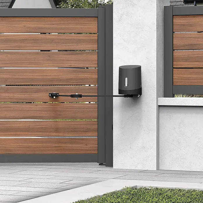 Avidsen Mecanismo de puerta de garaje Orane 510 con brazo articulado - Anchura puerta: 0 m - 2,5 m - Primer plano de un operador de puerta automático montado en un pilar de hormigón, abriendo una puerta de madera. Enfoque en el diseño moderno del operador.