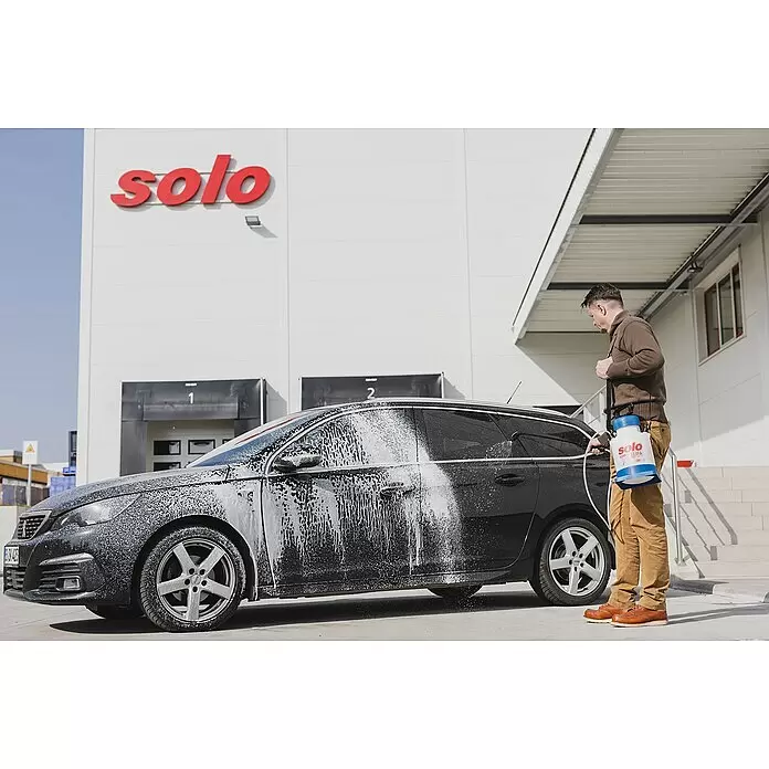 Solo Schaumsprüher Cleanline 333 FA - Füllmenge: 4 l - Ein Mann verwendet ein blau-weißes Solo clean 333FA Sprühgerät, um Reinigungsschaum auf ein schwarzes Auto aufzutragen.