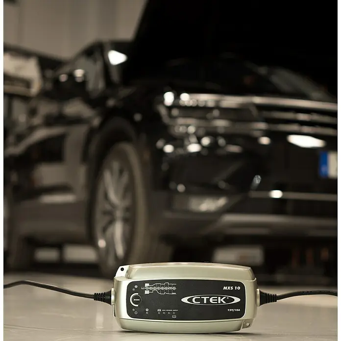 CTEK Automatik-Ladegerät MXS 10 EU - Ladestrom: 10 A, Kapazität: 20 Ah - 200 Ah - Ein CTEK MXS 10 Batterieladegerät vor einem Auto, das für die Batterieaufladung bereit ist.