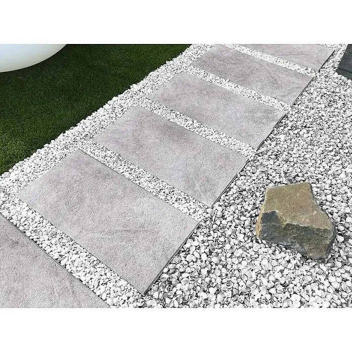 Diephaus Terrassenplatte Atlanta - 60 x 30 x 4 cm, Quarz, Beton - Trittplatten aus grauem Stein, eingebettet in weißen Kies und Zierschotter, schaffen einen modernen Gartenweg mit natürlicher Note.