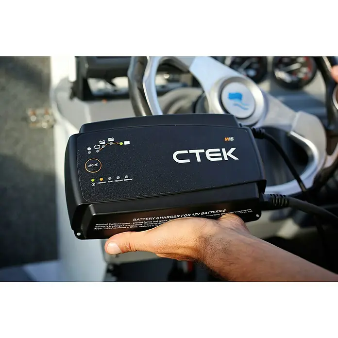 CTEK Automatik-Ladegerät M 15 EU - Kapazität: 28 Ah - 300 Ah - Nahaufnahme eines CTEK M15 Batterieladegeräts für 12V Batterien, das in einer Hand gehalten wird, mit Fokus auf Design und Funktionalität.