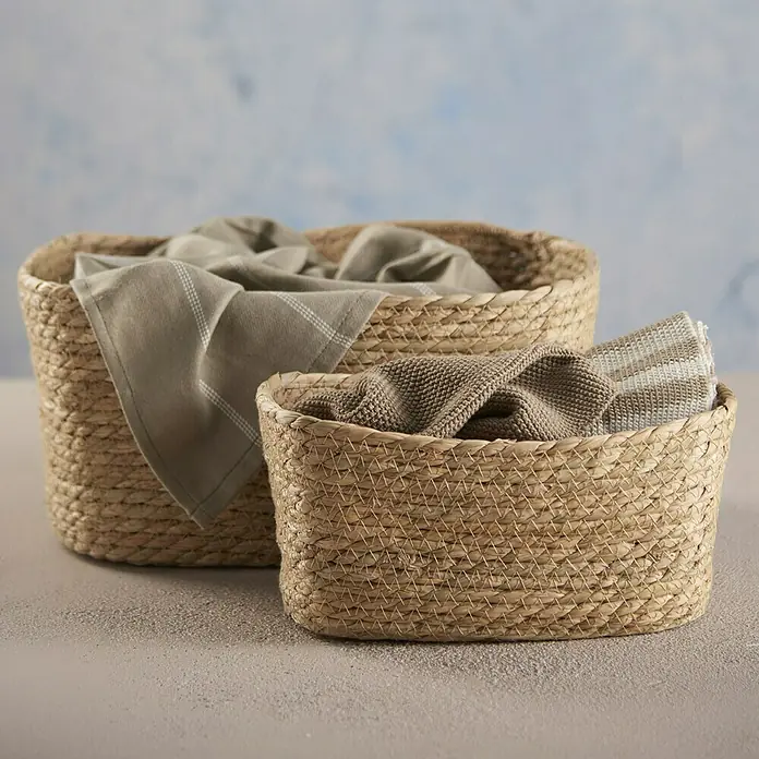 Cesta de junco - L x An x Al: 24 x 34 x 17 cm, Natural - Dos cestas decorativas hechas de material natural rellenas de textiles, ideales para un almacenamiento elegante en el hogar.