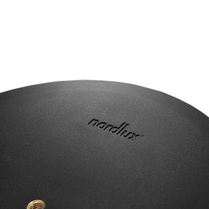 Nordlux Sponge Akku-Pendelleuchte Sponge - 4,8 W, Warmweiß - Nahaufnahme eines Nordlux-Produkts mit dem geprägten Logo auf einer strukturierten, schwarzen Oberfläche.