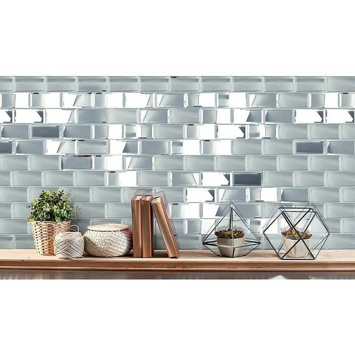 Mosaikfliese Mirror Metro XSPM 07 - 29,8 x 29,8 cm, Spiegel, Glänzend - Nahaufnahme einer Wand mit rechteckigen Spiegel-Fliesen. Dekorative Gegenstände wie Pflanzen und Bücher stehen auf einem Holzregal.