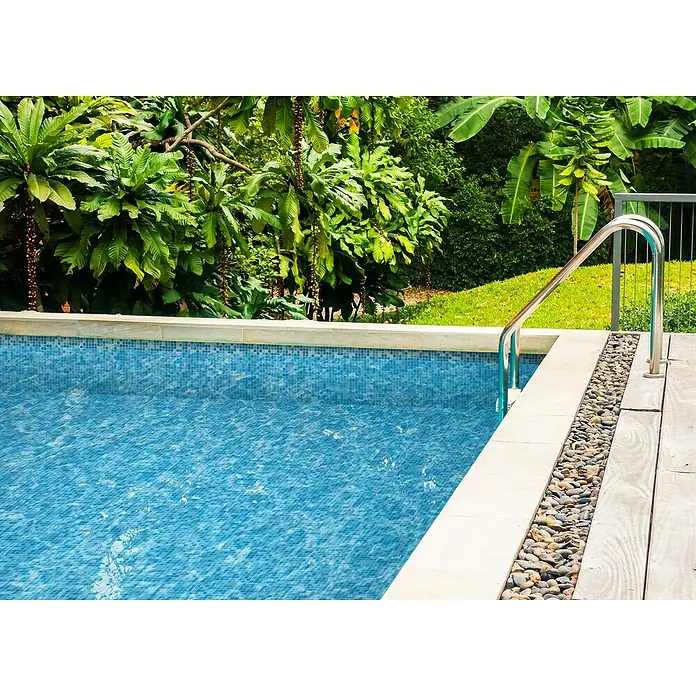 Mosaikfliese Quadrat Mix GM A 321P - 32,7 x 30,5 cm, Blau, Glänzend - Diese Nahaufnahme zeigt einen Swimmingpool mit blauen Mosaikfliesen, umgeben von üppigem Grün und einem silbernen Geländer.