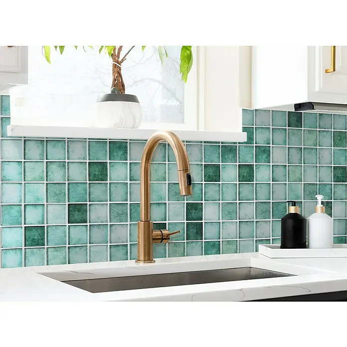 Mosaikfliese Quadrat Crystal SKY 789 - 31,6 x 31,6 cm, Grün, Glänzend - Nahaufnahme eines Küchenspülbeckens mit einem goldenen Wasserhahn und grün-blauen quadratischen Fliesen als Spritzschutz.