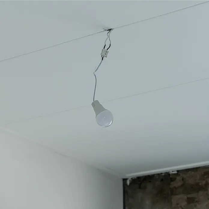 LED-Lampe Renovierlampe mit Steckklemme neutralweiß 1055 lm - E27, 10 W - Ein weißes LED-Leuchtmittel hängt an einem Kabel von einer weißen Decke, wodurch ein minimalistisches und funktionales Design entsteht.