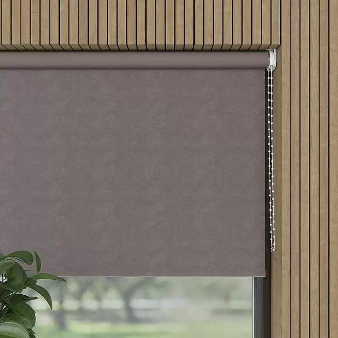 Verdunkelungsrollo Velvet - B x H: 80 x 190 cm, Taupe - Graues Stoff-Rollo mit Kette, am Fenster vor einer Holzlamellenwand mit verschwommenem Grünblick.