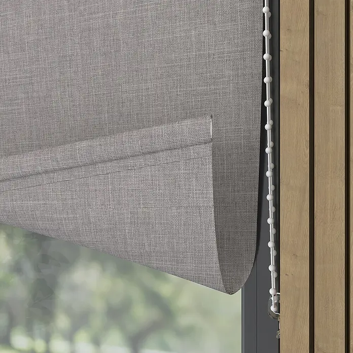 Verdunkelungsrollo Structure - B x H: 140 x 190 cm, Kalk - Nahaufnahme einer grauen Rollmarkise mit Zugband, die teilweise vor einem Fenster hängt, das einen Blick ins Grüne freigibt.